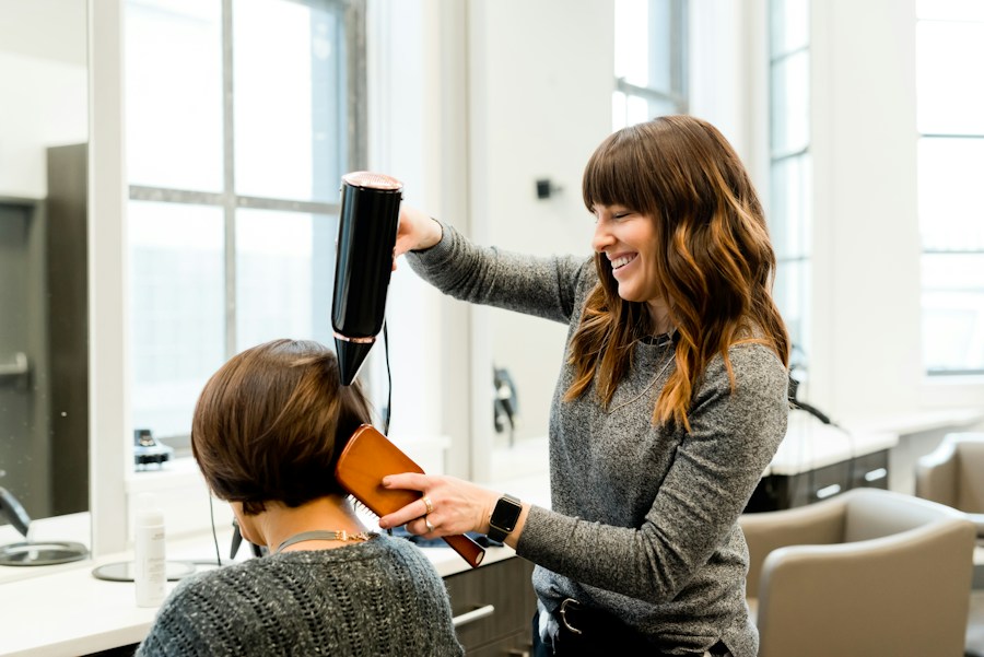 A smiling hairdresser styling a client’s hair at home